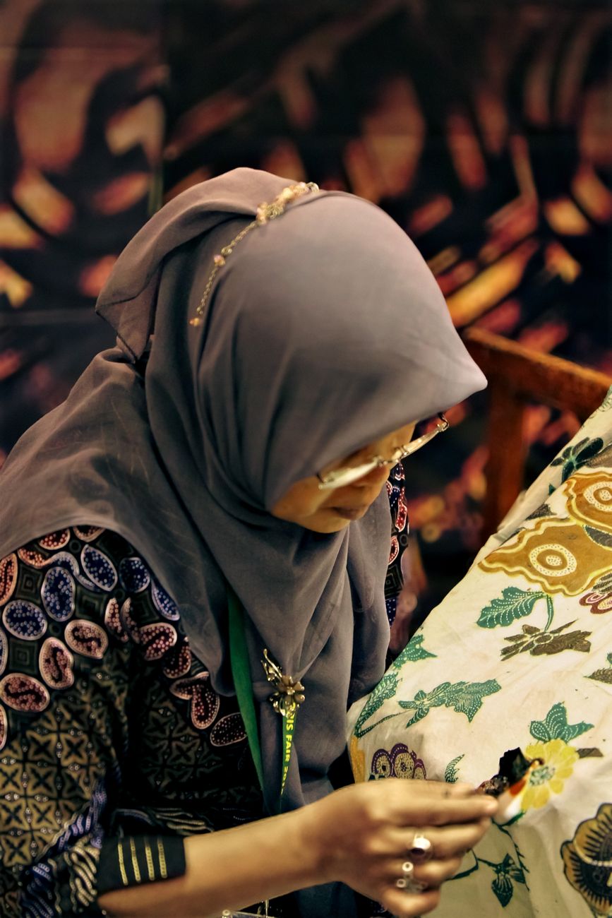 Pengrajin batik memindai QR code pada layar smartphone pelanggan.